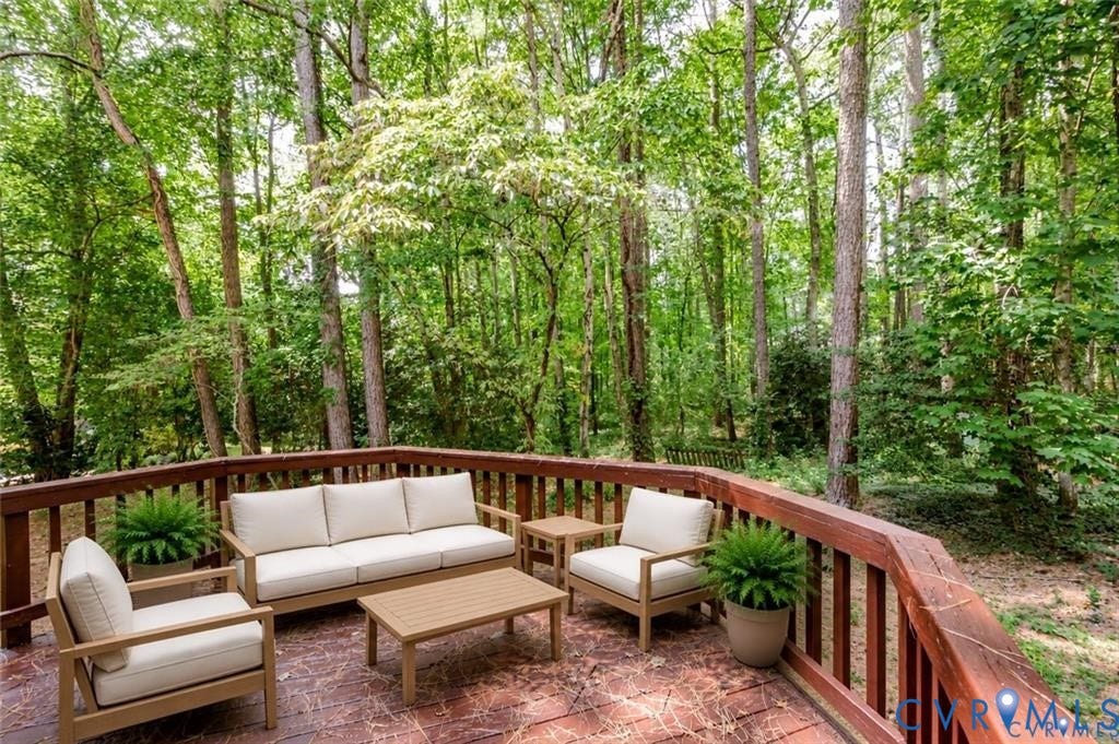 Expansive wooden deck with a durable railing system, set against a backdrop of mature trees and natural landscaping
