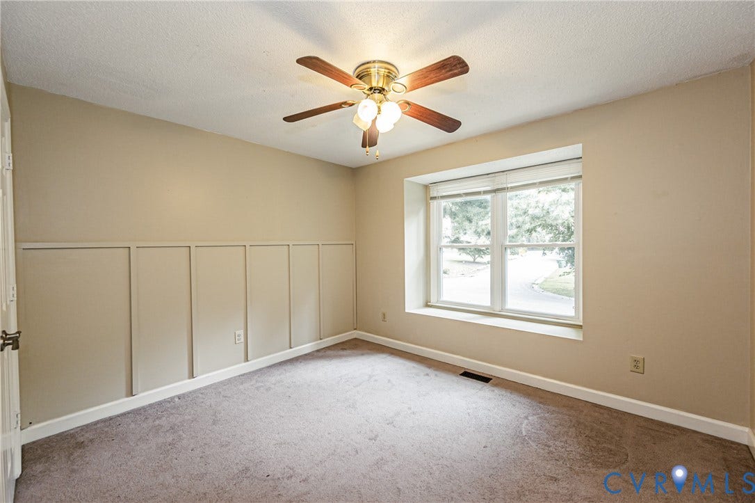 Vaulted ceiling featuring a ceiling fan with integrated lighting, wall paneling, a large window, and carpet flooring