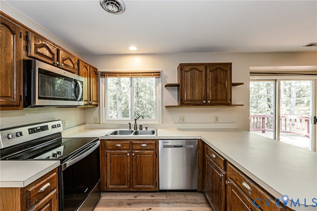 Kitchen with wood-finish cabinetry, stainless steel appliances, and a double basin sink