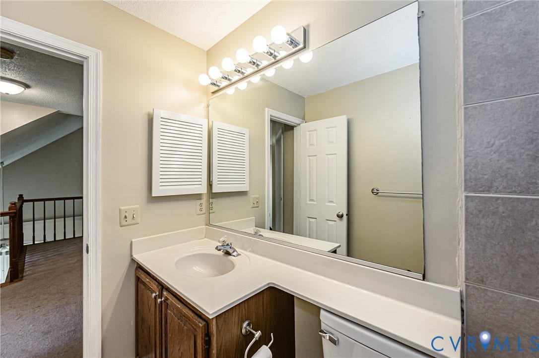 Vanity with an integrated sink, wood-finish cabinetry, and a large wall-mounted mirror