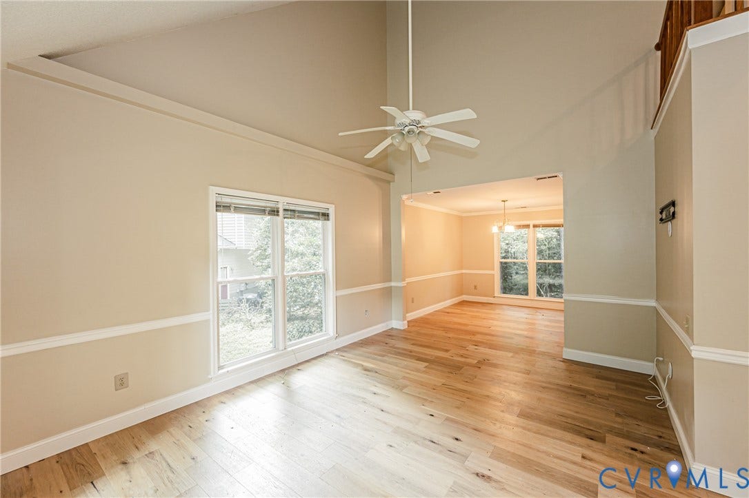 Vaulted ceiling with a ceiling fan, light wood-finish flooring, and crown molding