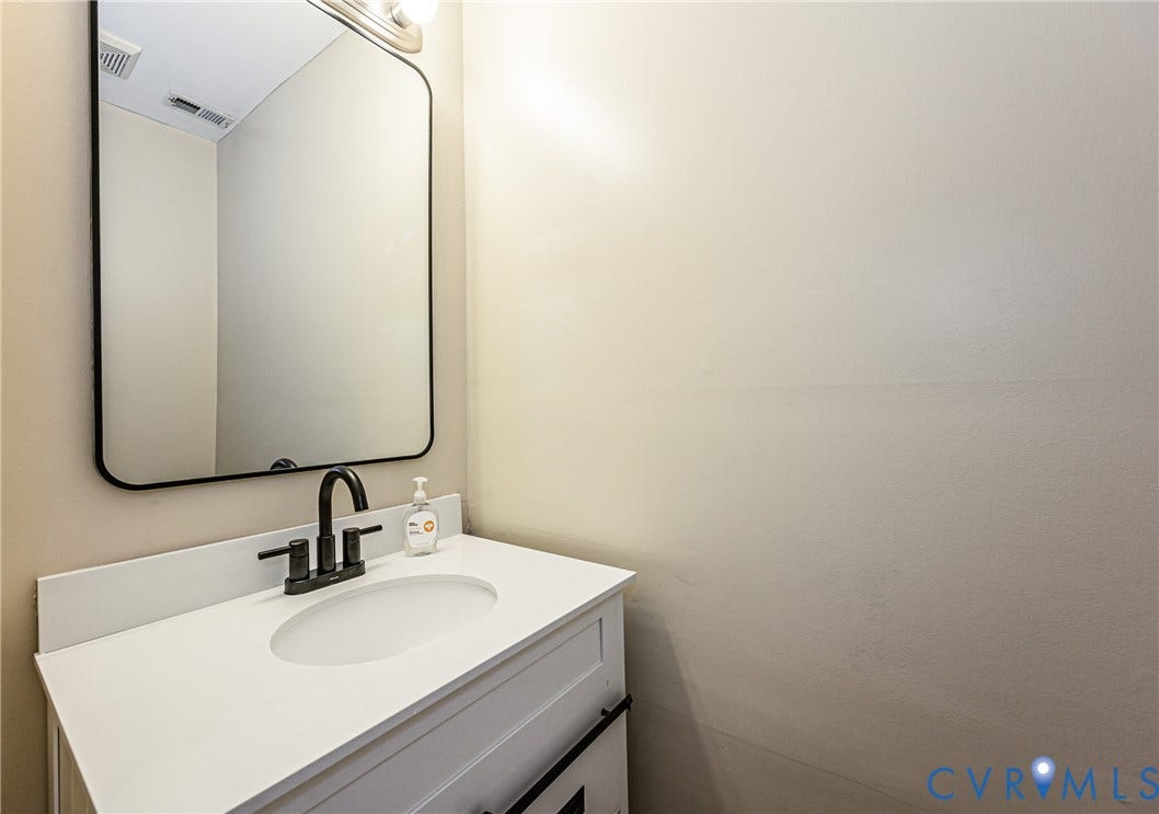 White vanity with shaker-style door, white countertop, and integrated sink