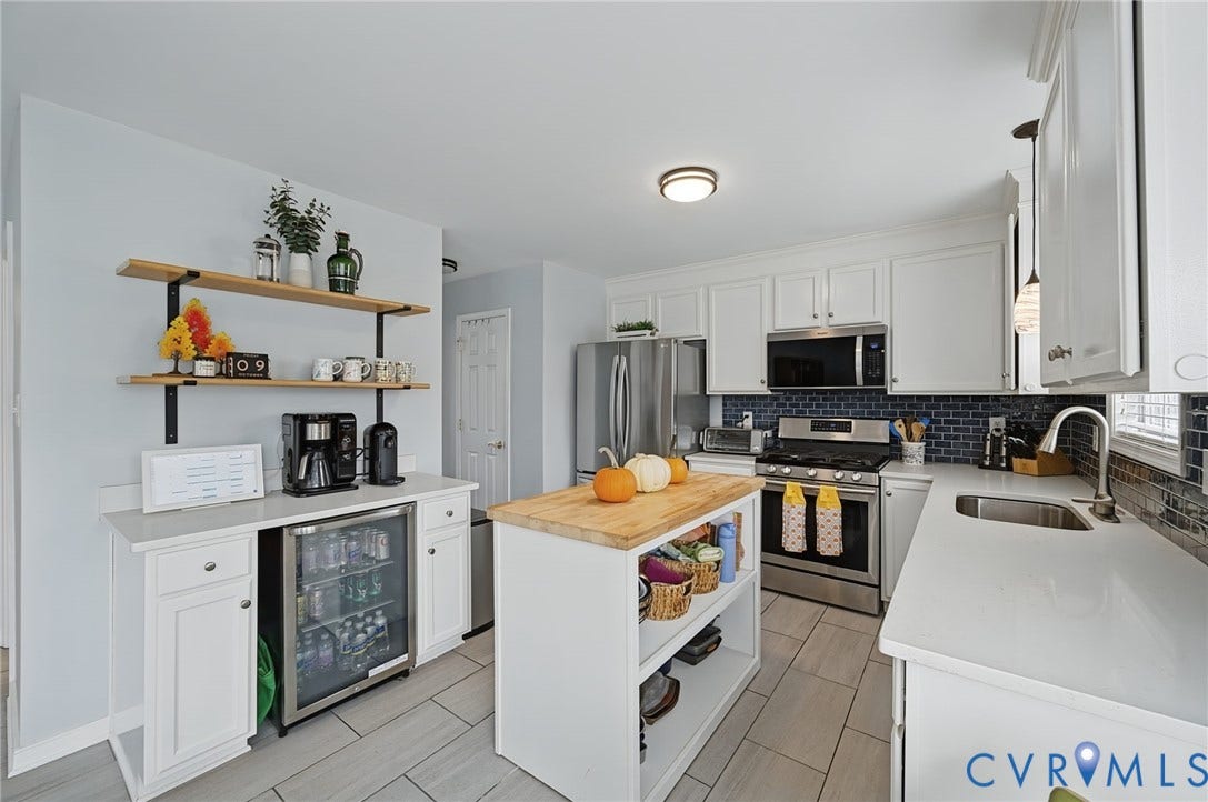 3912 Houze Terrace, Spring Lake, Henrico, VA 23060 White cabinetry with stainless steel appliances, blue tile backsplash, light-toned countertop, and a center island with a wood-finish top