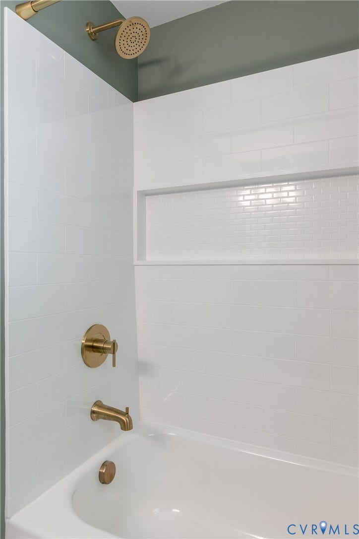2207 Locbury Lane, Henrico, VA 23228 Bathtub surround featuring white subway tile, a built-in recessed niche, and metallic-finish hardware including a showerhead, faucet, and handle