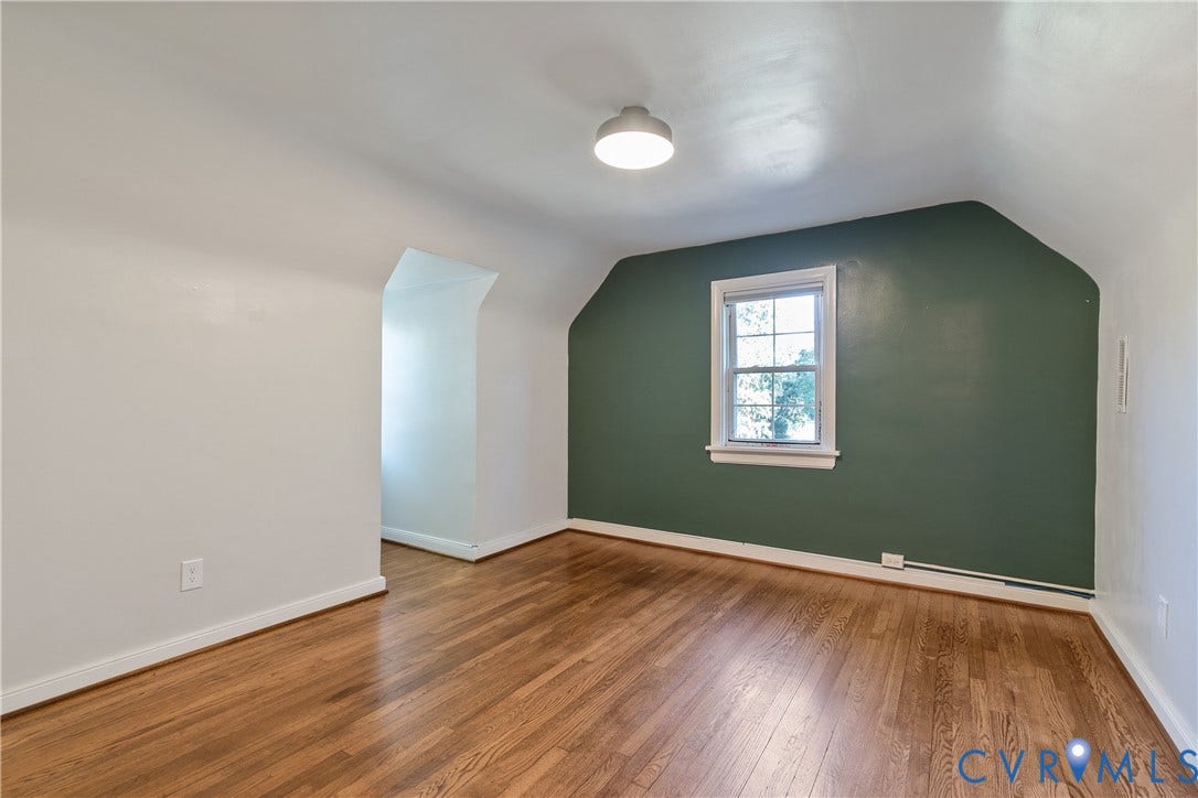 2207 Locbury Lane, Henrico, VA 23228 Interior space featuring wood-finish flooring, vaulted ceilings, a prominent dark green accent wall, and a multi-pane window