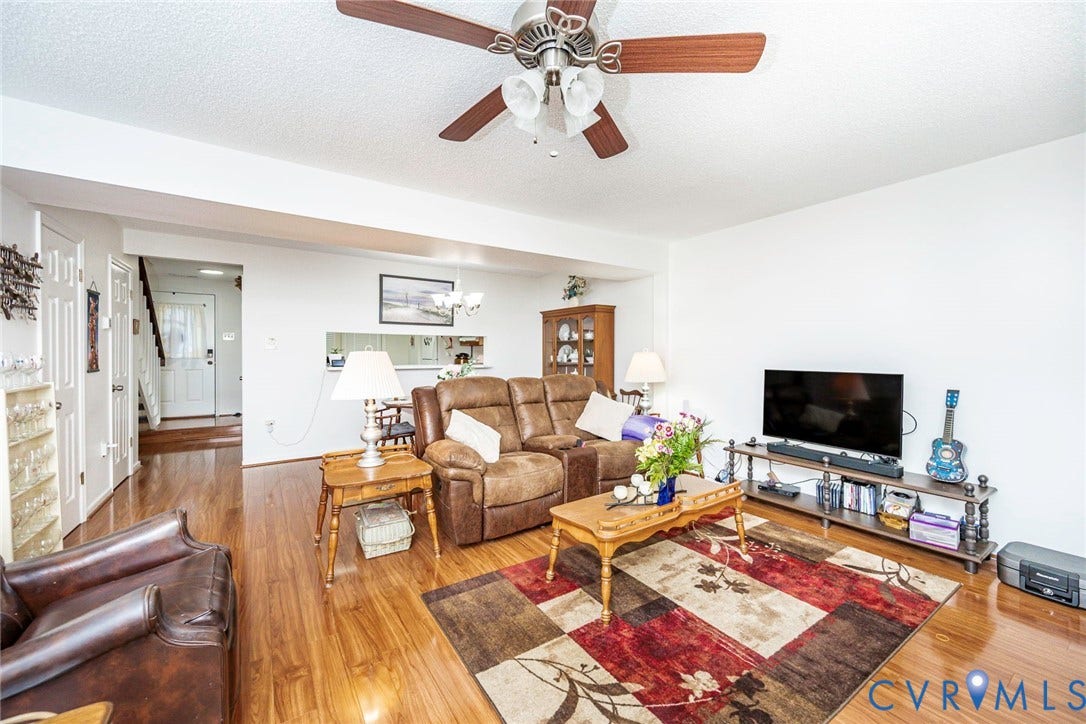 Comfortable living room with fan and fireplace and opens to the back deck and patio area.