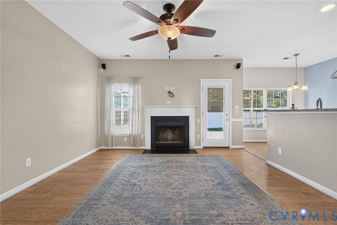 6852 Watch Harbour Circle, Hayes, VA 23072 Wood-finish flooring with a white-trimmed window, fireplace with white mantel, a ceiling fan with integrated lighting, and a white-framed glass paneled door