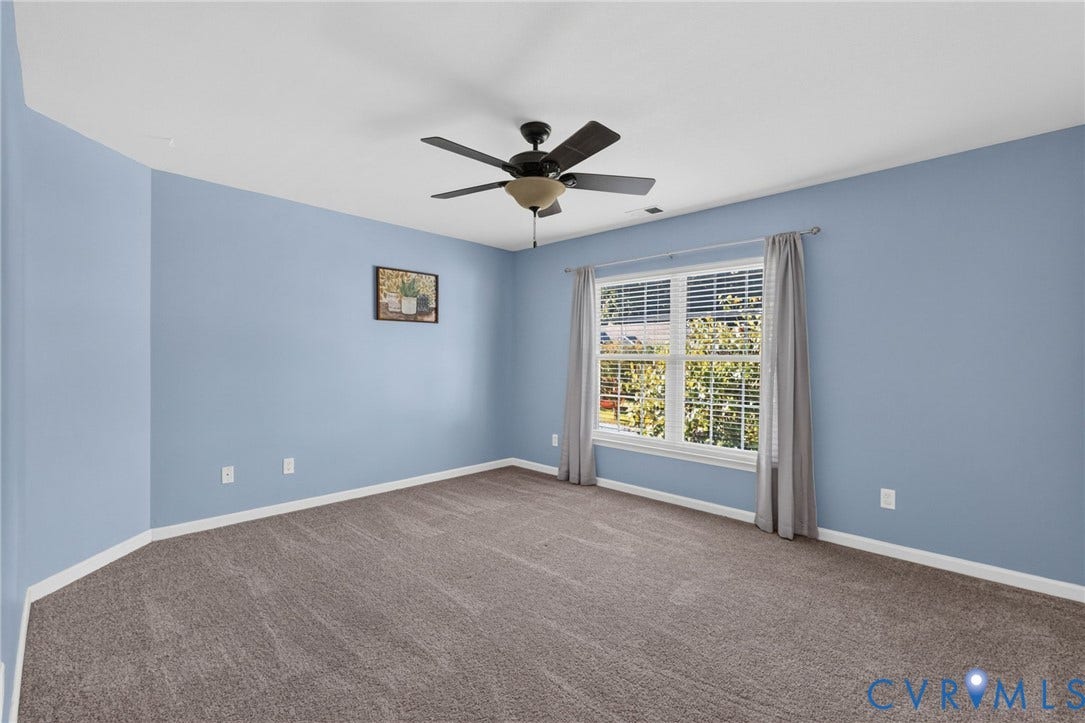 6852 Watch Harbour Circle, Hayes, VA 23072 Expansive room featuring light blue walls, a large window with privacy blinds, and a ceiling fan with integrated lighting