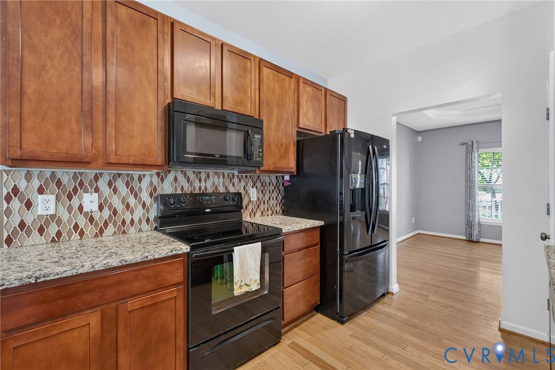 6852 Watch Harbour Circle, Hayes, VA 23072 Kitchen featuring wood-finish cabinetry, speckled countertops, a decorative tile backsplash, and black appliances