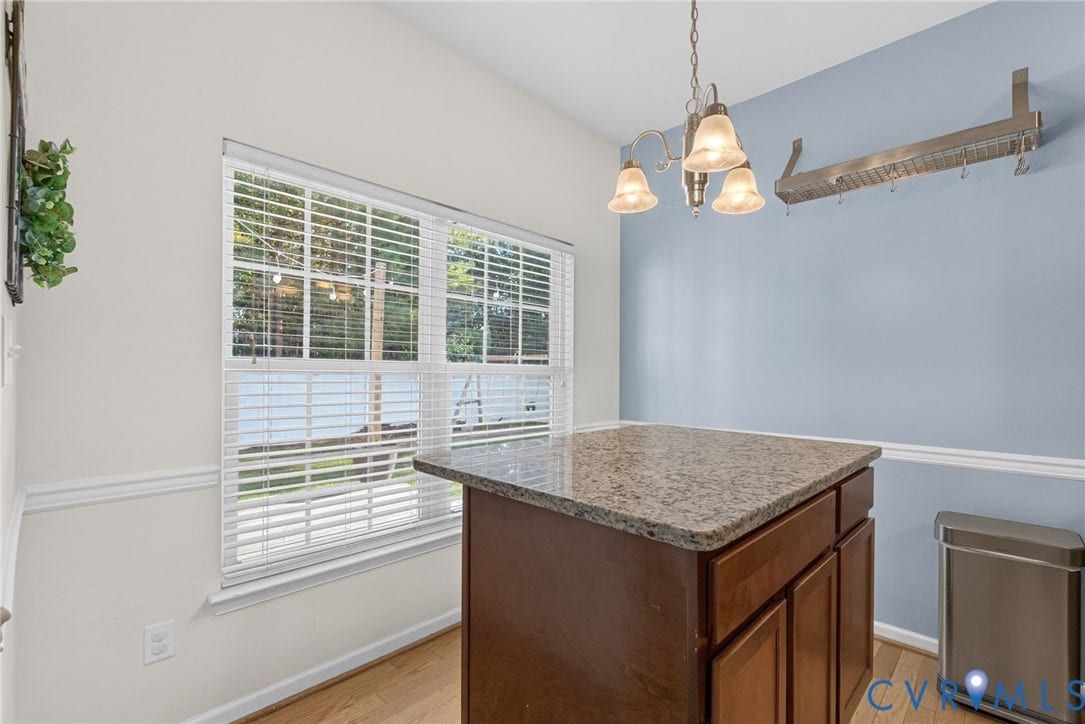 6852 Watch Harbour Circle, Hayes, VA 23072 Window with horizontal blinds, wood-finish flooring, accent wall, chair rail molding, and a kitchen island with a stone countertop