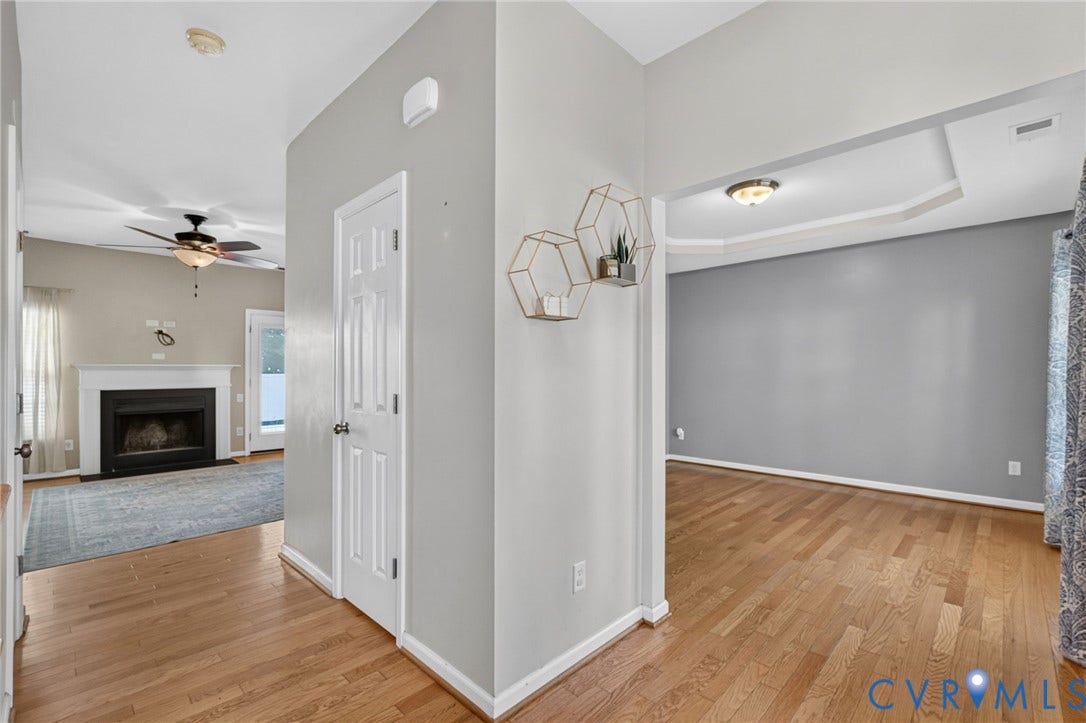 6852 Watch Harbour Circle, Hayes, VA 23072 Wood-finish flooring throughout, tray ceiling with recessed lighting, and a fireplace with a white mantel