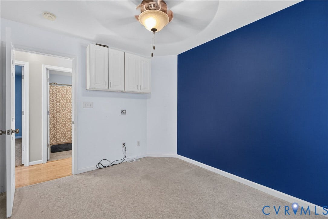 6852 Watch Harbour Circle, Hayes, VA 23072 Carpeted flooring, ceiling fan with integrated lighting, wall-mounted cabinetry, and a vibrant accent wall