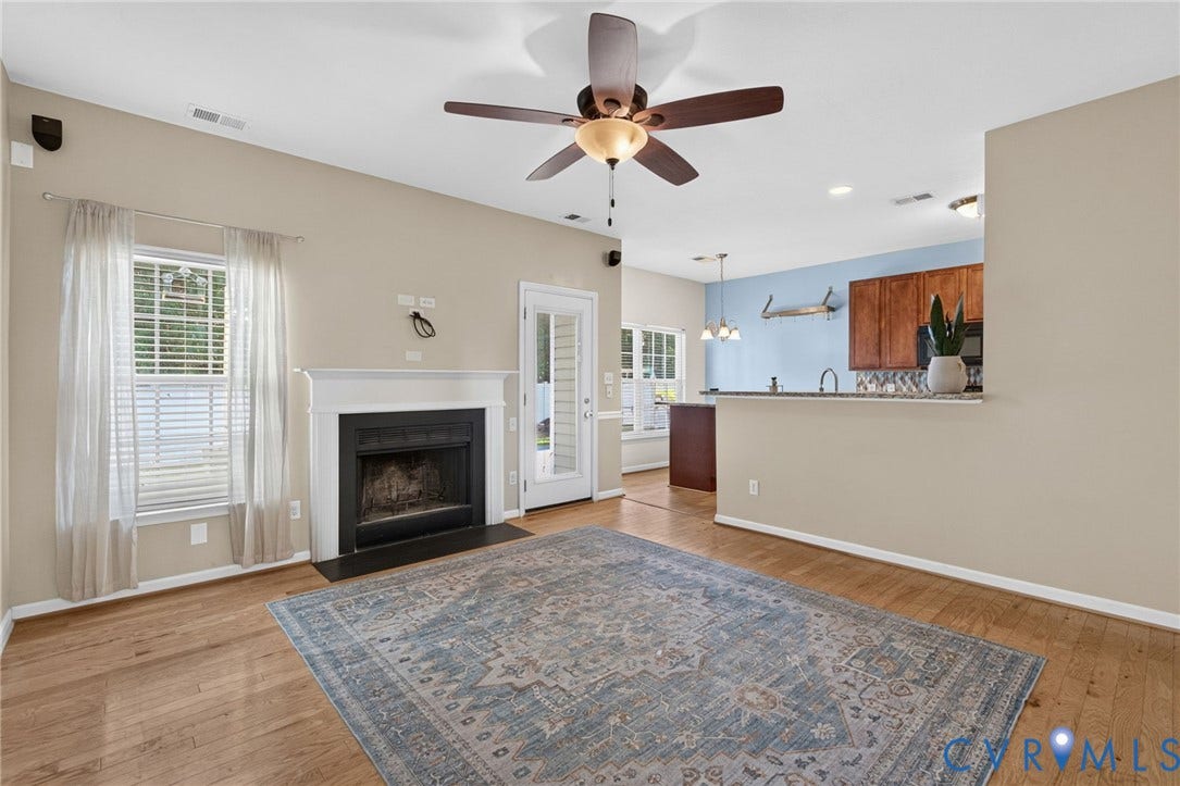 6852 Watch Harbour Circle, Hayes, VA 23072 Wood-finish flooring throughout, featuring a fireplace with a white mantel, ceiling fan, and French door