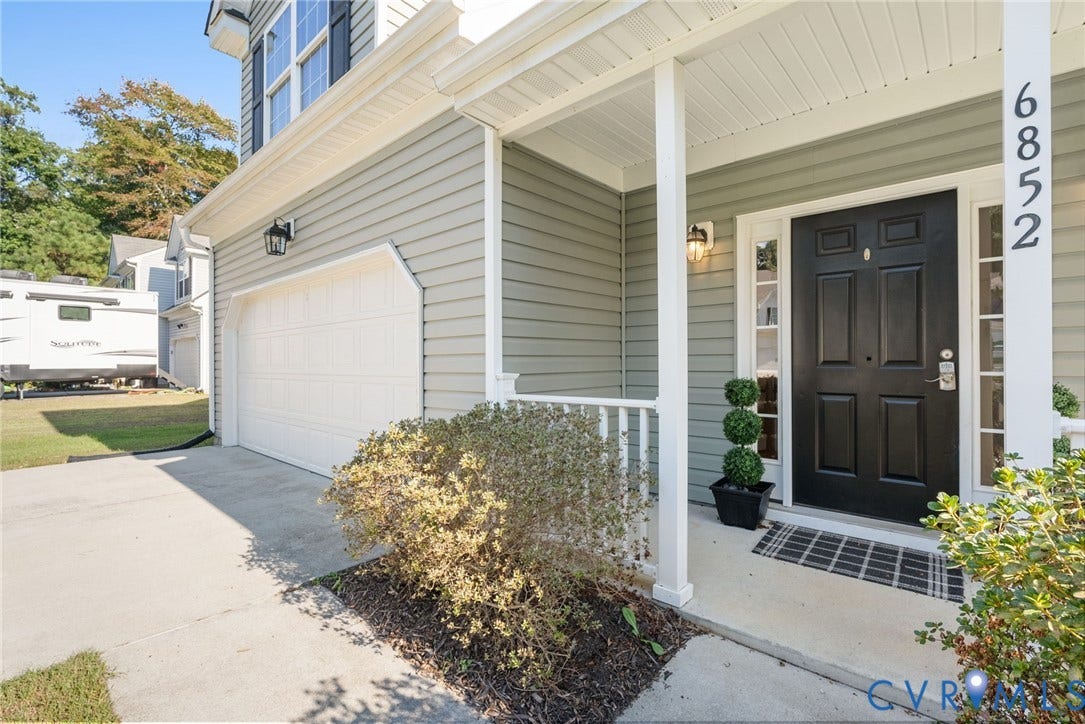 6852 Watch Harbour Circle, Hayes, VA 23072 Light-colored siding exterior with white trim, covered front porch, black paneled front door with sidelights, and an attached garage with a white door