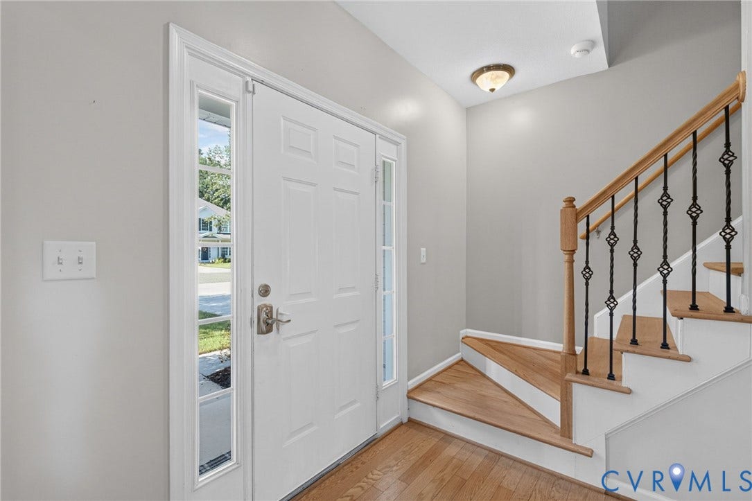 6852 Watch Harbour Circle, Hayes, VA 23072 Entryway featuring a white paneled door with sidelights, wood-finish flooring, and a staircase with a wood handrail and decorative iron balusters