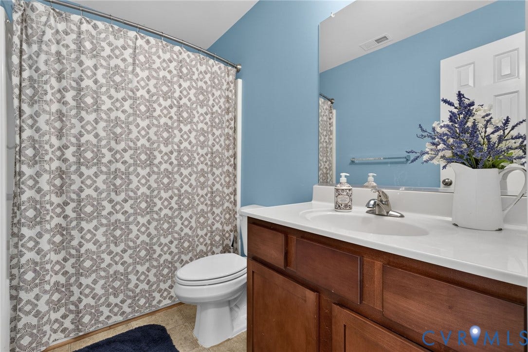 6852 Watch Harbour Circle, Hayes, VA 23072 Vanity with integrated sink, wood-finish cabinetry, and an expansive mirror