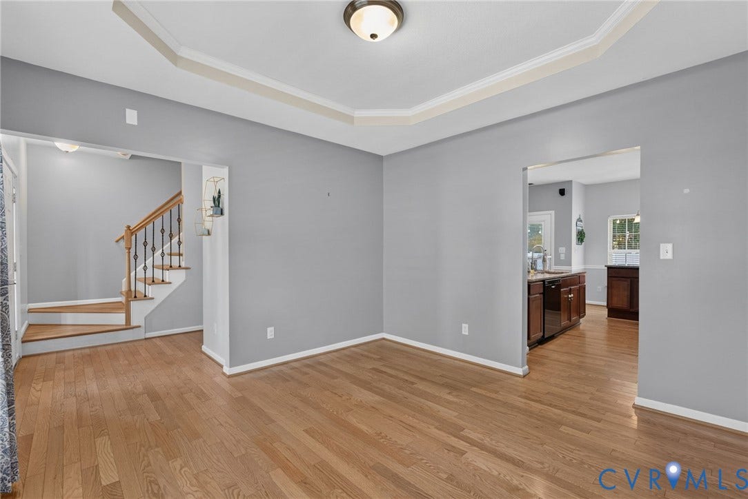 6852 Watch Harbour Circle, Hayes, VA 23072 Hardwood flooring, tray ceiling, recessed lighting, wood-finish staircase with wrought iron spindles, and an open doorway to the kitchen