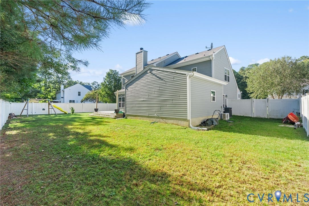 6852 Watch Harbour Circle, Hayes, VA 23072 Expansive green lawn with a white privacy fence, a concrete patio, and a two-story exterior with light gray siding