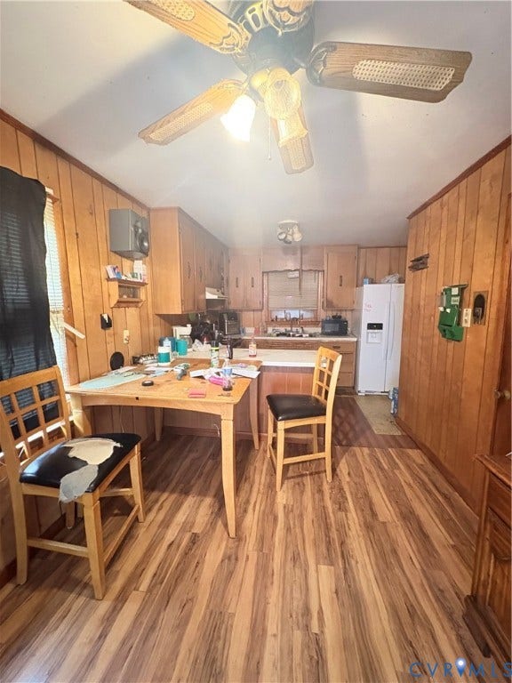 Wood-finish flooring throughout, wood paneling, and a ceiling fan with light fixture