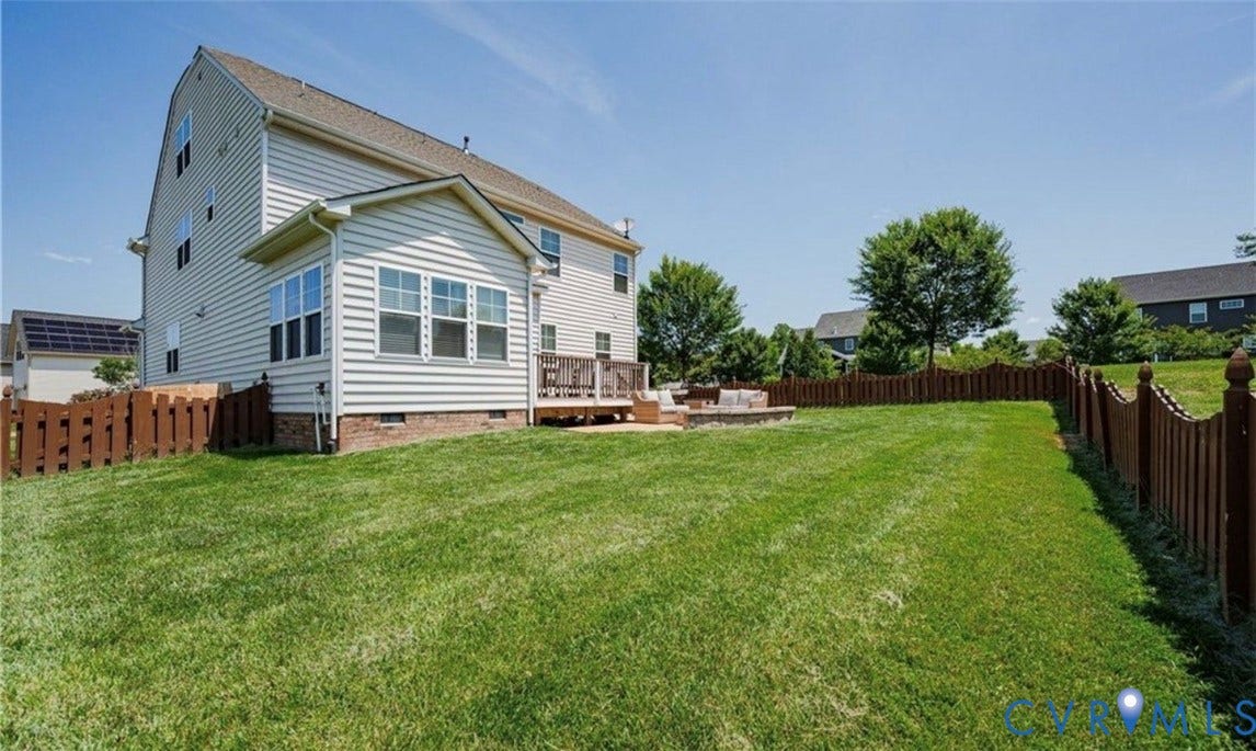 16001 Lost Crop Drive, Moseley, VA 23120 Expansive grassy yard with wood fencing, a stone patio, and a wood deck