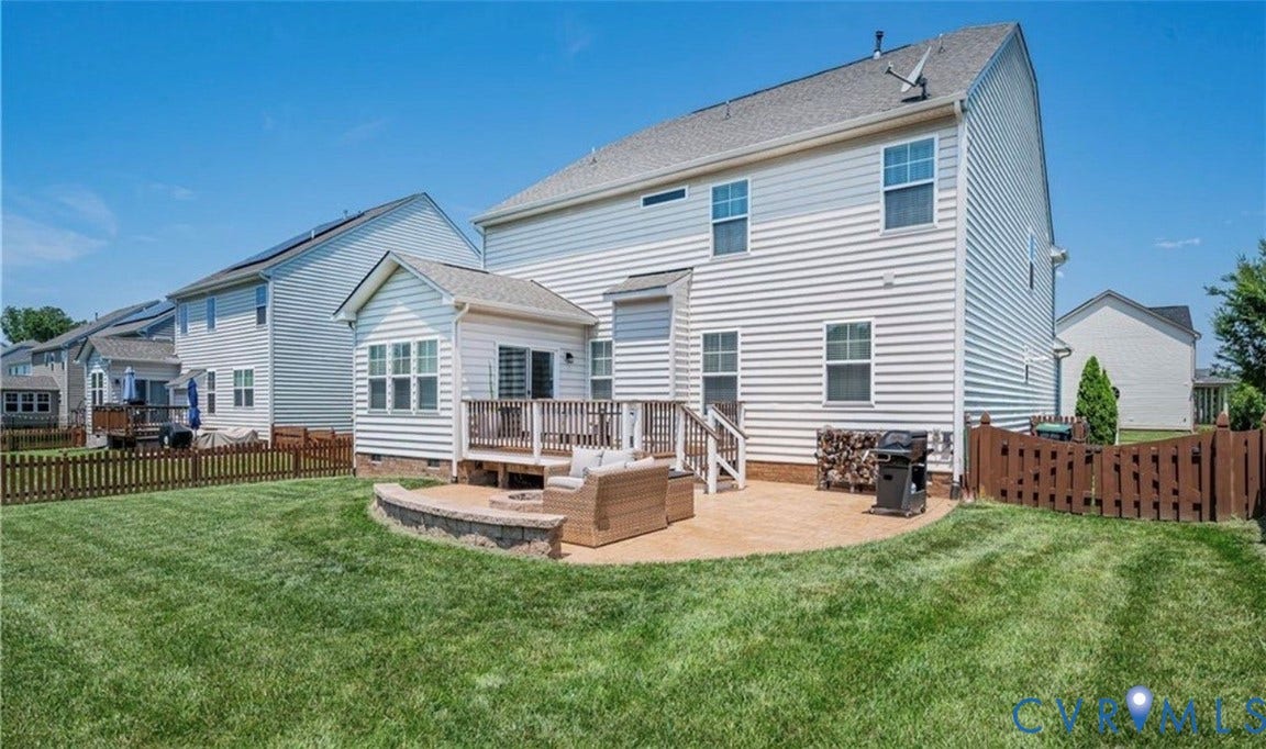 16001 Lost Crop Drive, Moseley, VA 23120 Expansive lawn with a wooden privacy fence, a multi-level deck, and a stone-paver patio with a built-in retaining wall