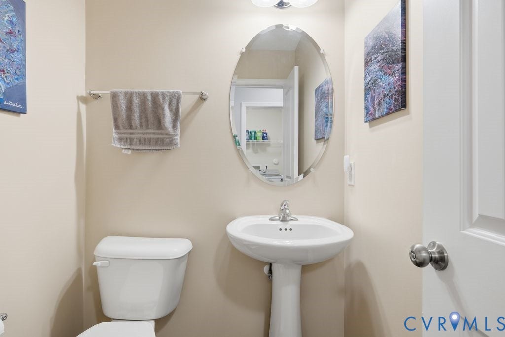 2490 Mountain Road, Glen Allen, VA 23060 White pedestal sink with a chrome single-handle faucet, oval wall-mounted mirror, and wall-mounted metal towel bar