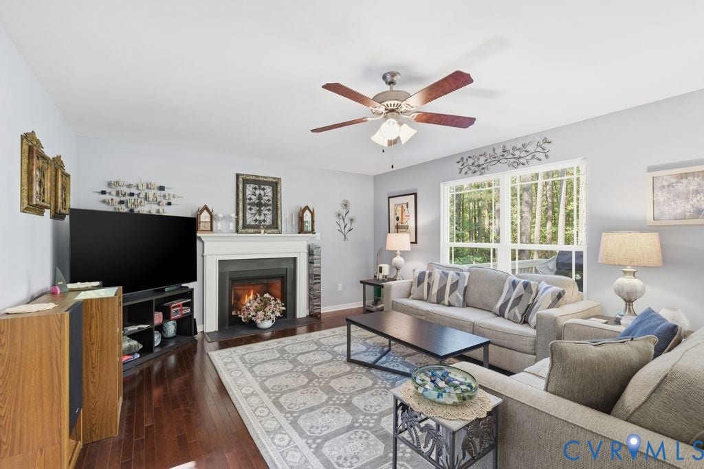2490 Mountain Road, Glen Allen, VA 23060 Living area featuring dark wood-finish flooring, a fireplace with a white mantel, and a ceiling fan with integrated lighting