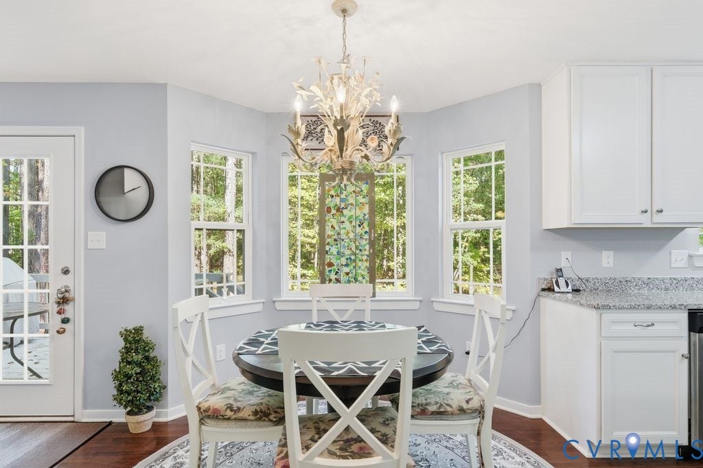 2490 Mountain Road, Glen Allen, VA 23060 Bay area featuring three windows with natural light, ornate chandelier, white shaker-style cabinetry, stone-patterned countertops, and dark wood-finish flooring