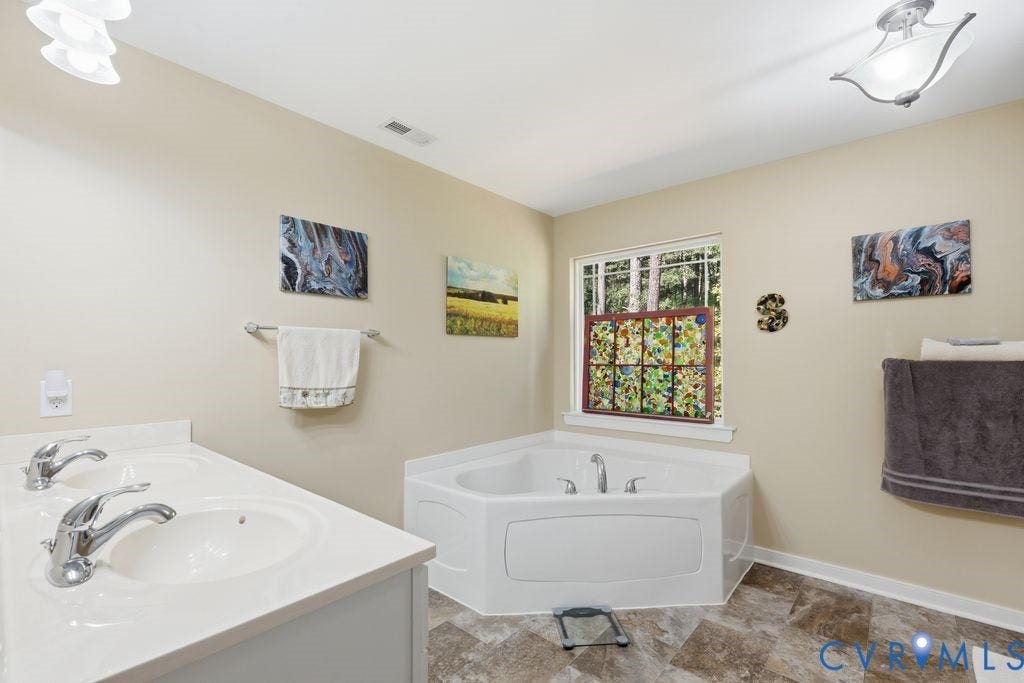 2490 Mountain Road, Glen Allen, VA 23060 Corner soaking tub with tile surround, dual-sink vanity with solid surface countertop, chrome fixtures, and tile flooring