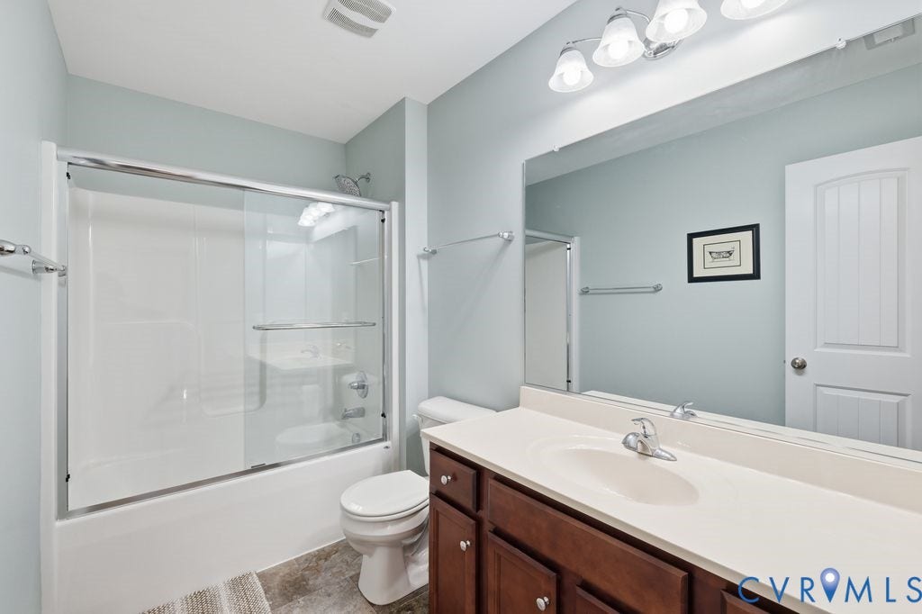 2490 Mountain Road, Glen Allen, VA 23060 Bathroom featuring a vanity with dark wood-finish cabinetry, integrated countertop with a sink, full-width wall mirror, and a shower-tub combination with sliding glass doors