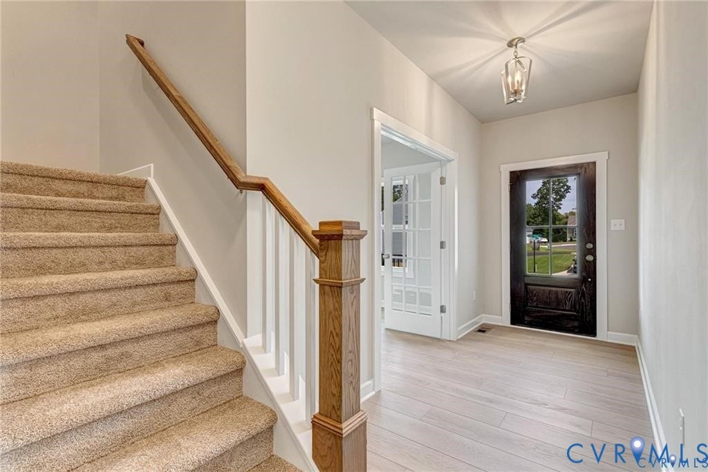 Foyer with wood-finish flooring and a contemporary pendant light fixture