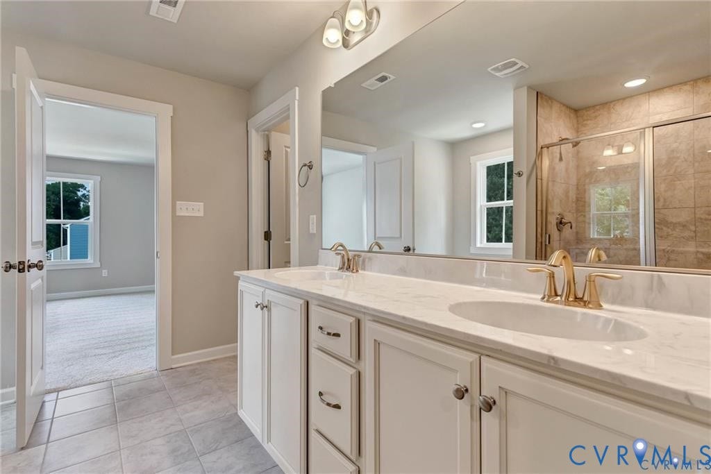 Double vanity with dual undermount sinks, gold-tone fixtures, and a spacious mirror