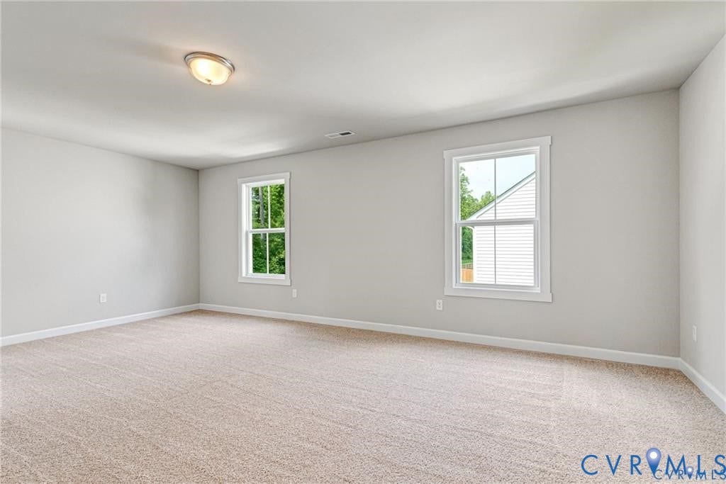 Neutral tone wall paint, carpeted flooring, two windows with white trim, and a flush mount ceiling light