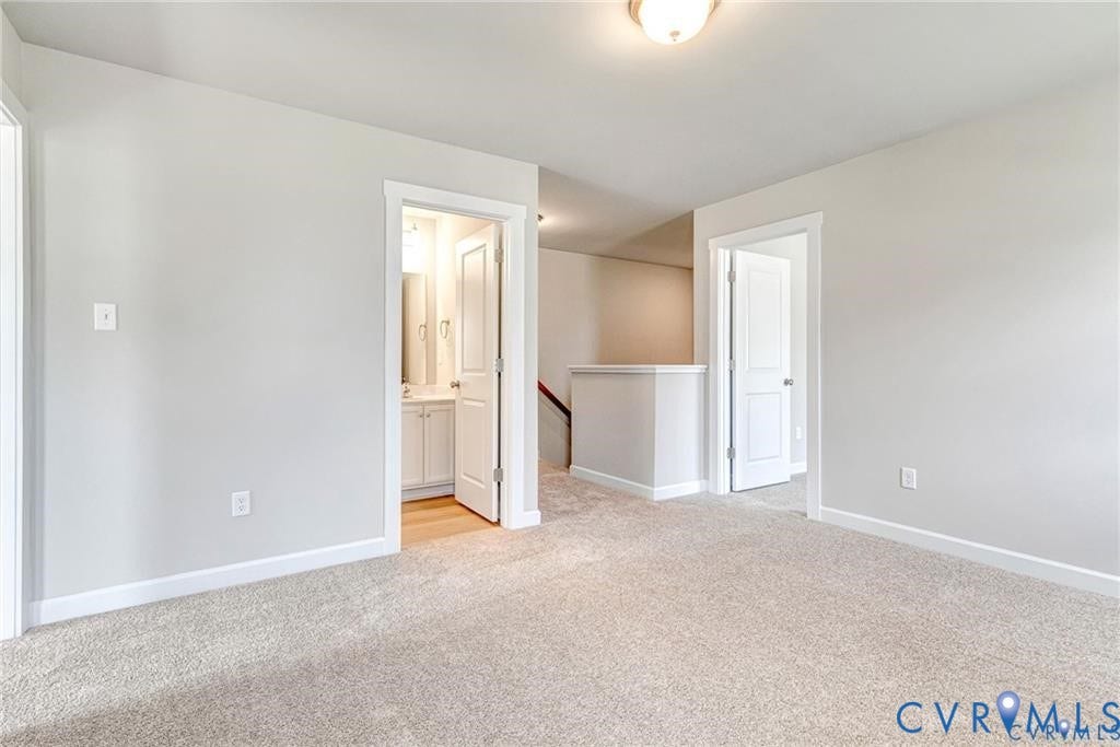 Carpeted hallway with light neutral wall tones, white trim, and a semi-flush mount ceiling fixture