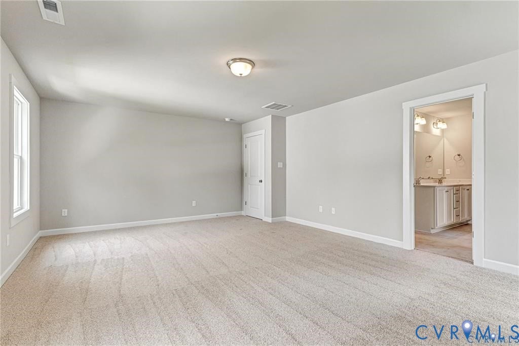 Carpeted flooring, neutral wall tones, window for natural light, overhead lighting, and white trim throughout