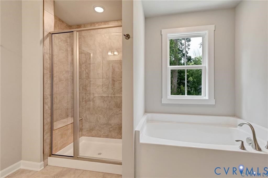 Glass-enclosed shower with a tiled surround, built-in bench, and a standalone soaking tub with a window