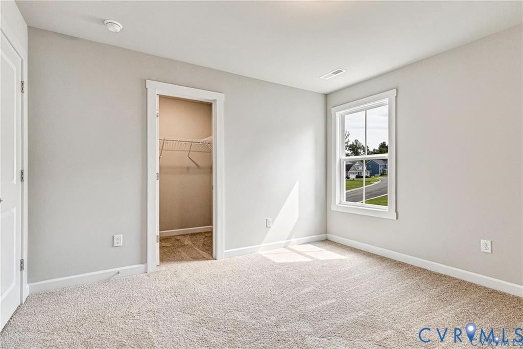 Neutral wall paint, carpeted flooring, a single window, and a built-in closet with wire shelving