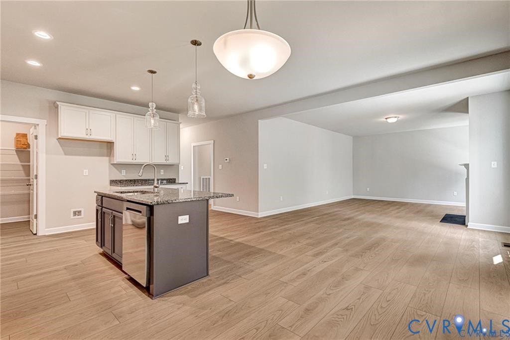 Kitchen island with granite countertop, stainless steel dishwasher, and pendant lighting