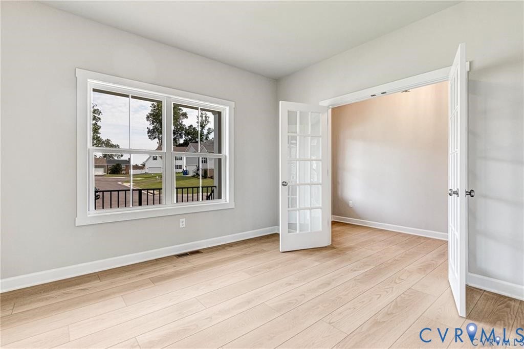 Light wood-finish flooring, white trim, and a window with a black railing