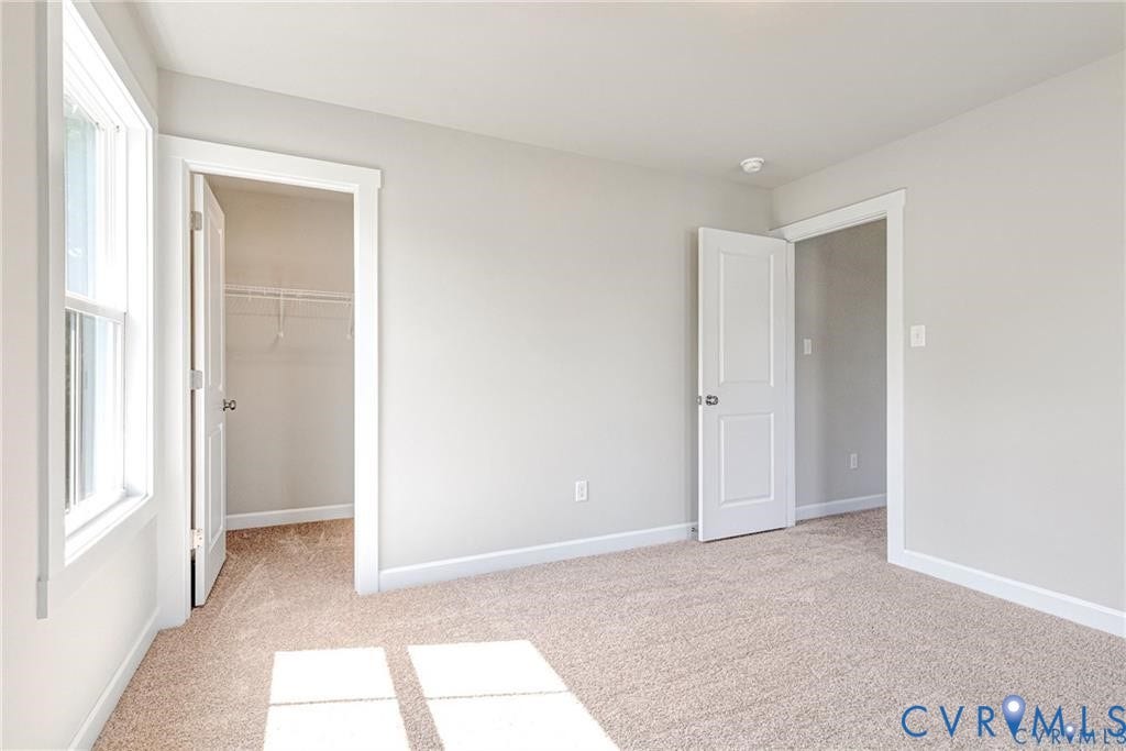 Neutral wall paint, carpet flooring, a window with white trim, and a closet with wire shelving