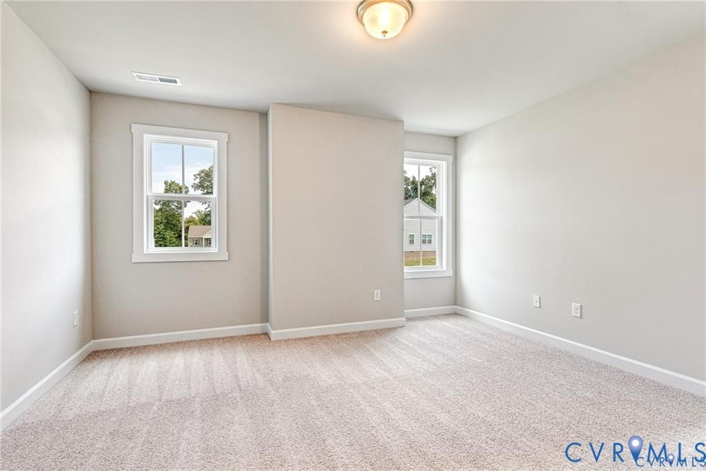 Two windows with white trim, light-colored carpeting, neutral wall paint, and a ceiling-mounted light fixture
