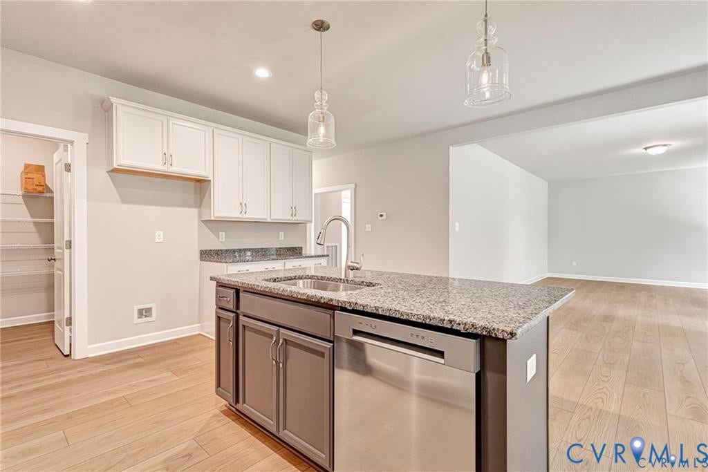 Kitchen featuring a center island, stainless steel dishwasher, undermount sink, granite countertops, and wood-finish flooring