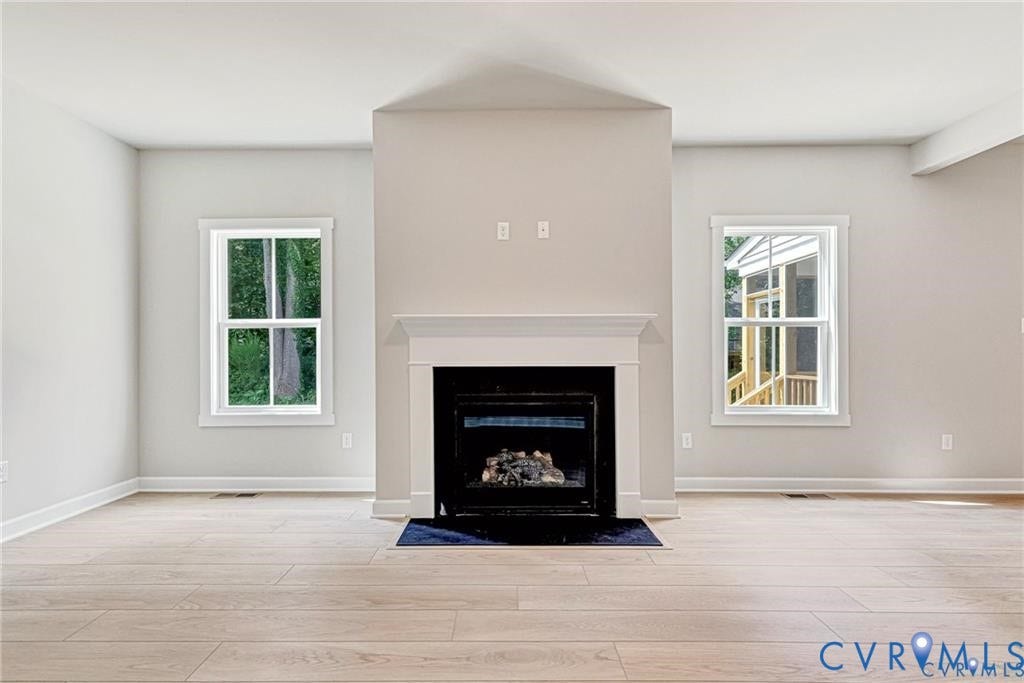 Fireplace with a white mantel, wood-finish flooring, and white trim windows