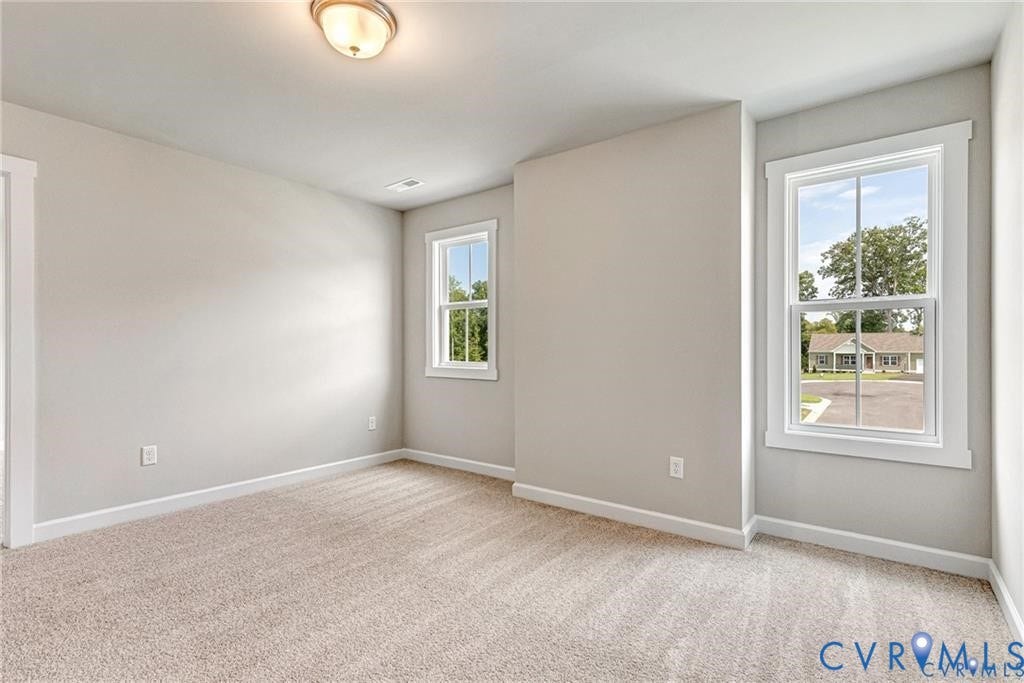 Soft neutral wall finishes, plush carpet flooring, multiple windows, and a flush mount ceiling light fixture