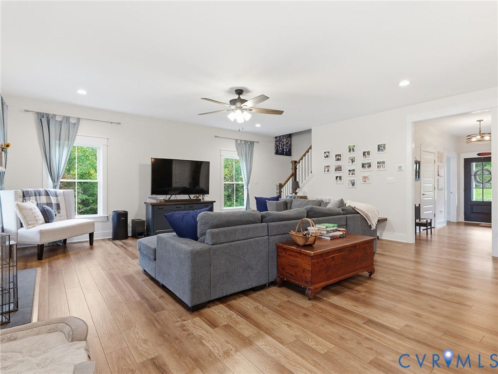 Open-concept interior featuring wood-finish flooring, recessed lighting, double-hung windows, and a ceiling fan