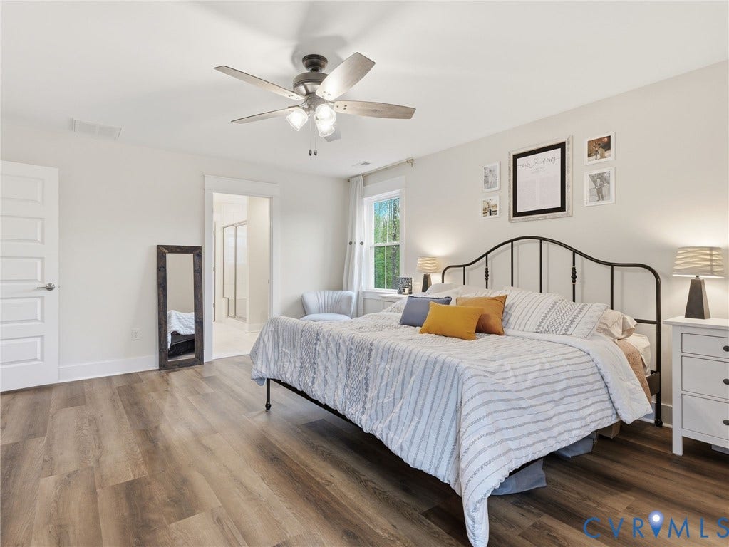 Bedroom featuring wood-finish flooring, a multi-blade ceiling fan with integrated lighting, a single-hung window, and a multi-panel interior door