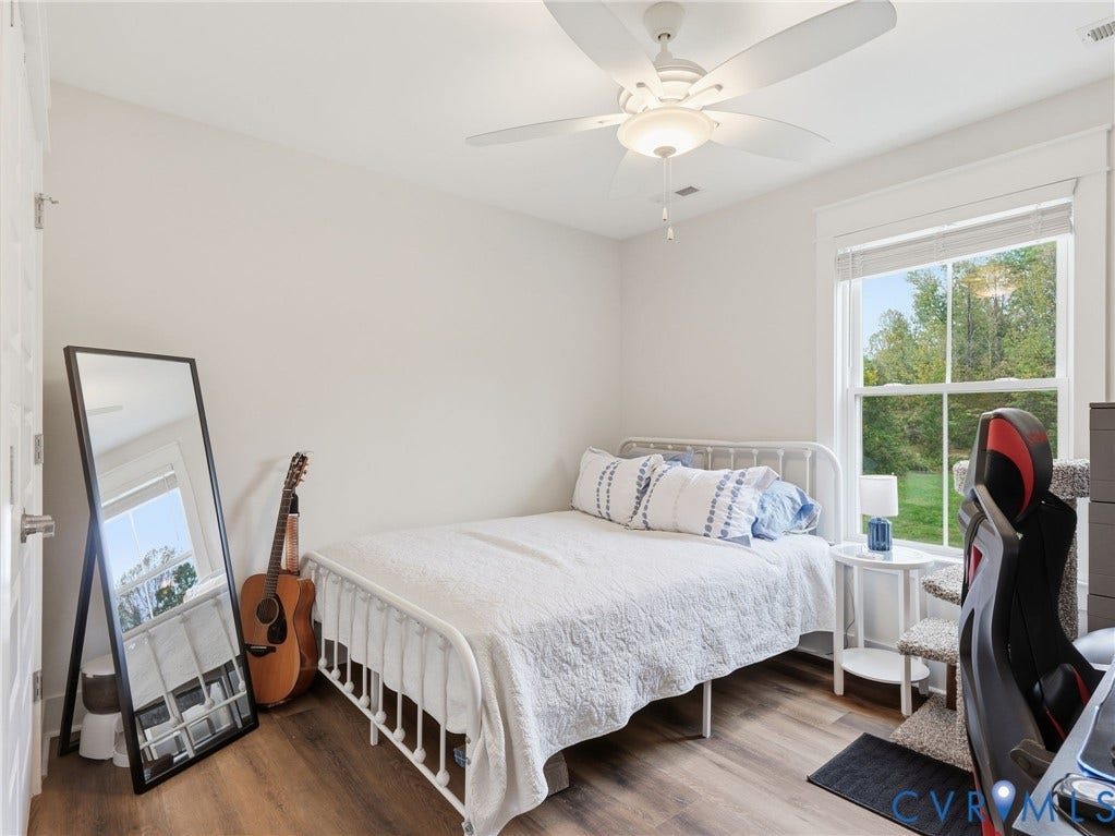 Room featuring wood-finish flooring, a neutral color palette, a ceiling fan with integrated lighting, and a window with white trim