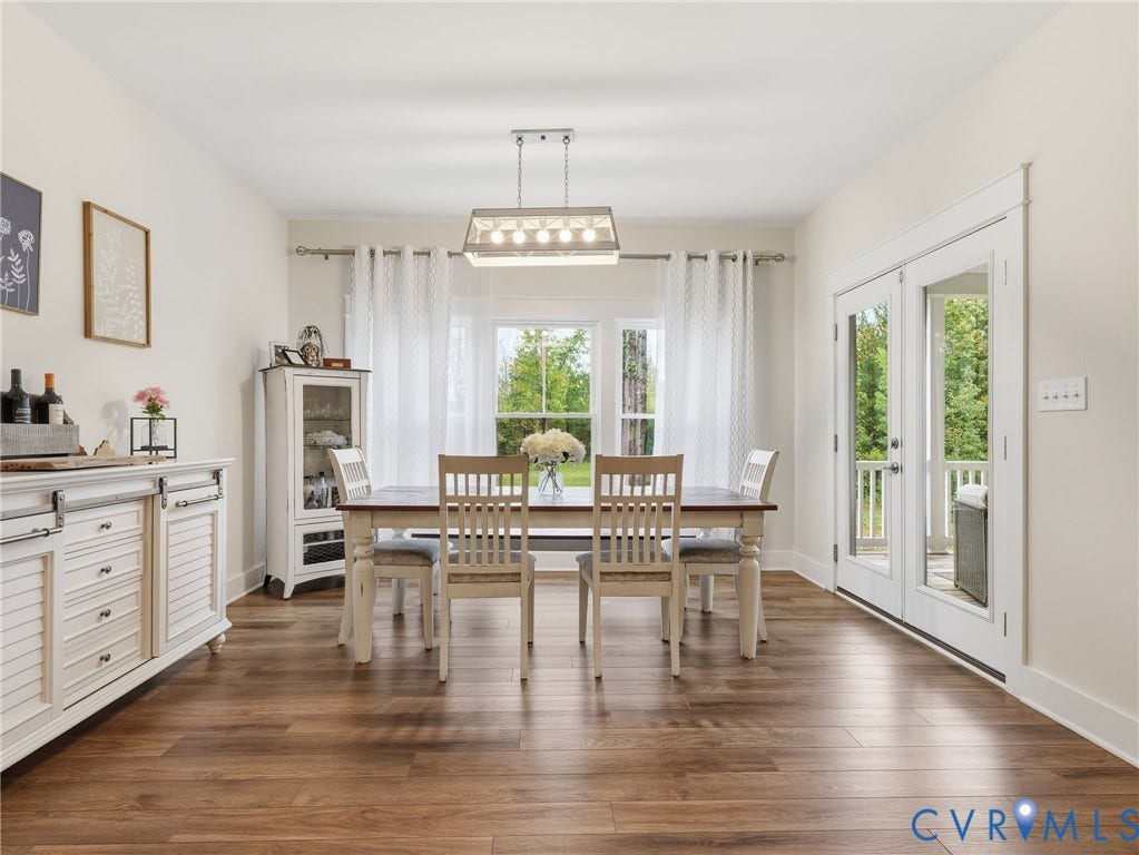 Dining area featuring wood-finish flooring, a rectangular multi-light pendant fixture, double glass-panel doors, and crisp white millwork casing