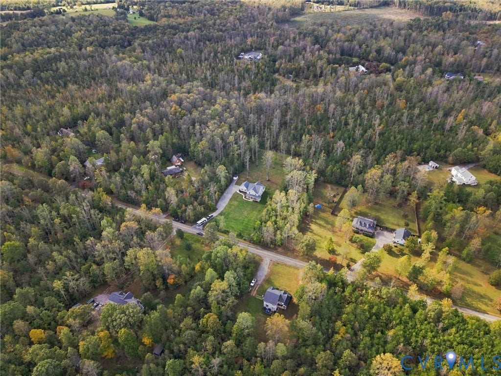 Aerial perspective of a multi-acre wooded landscape featuring expansive forest canopy, paved road access, and distinct cleared parcels