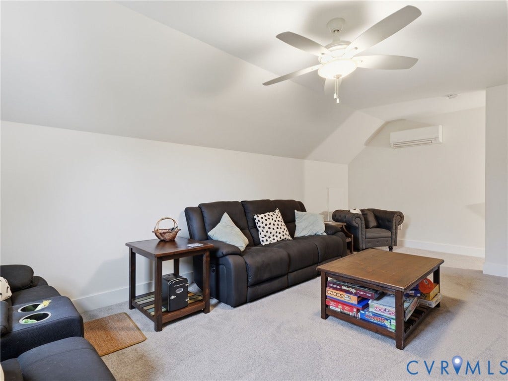 Vaulted ceiling featuring a central multi-blade ceiling fan and a wall-mounted ductless climate control unit
